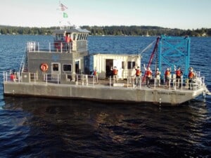 APL-UW Research Vessel Russell Davis Light on the water, with several APL-UW researchers on its deck waving to the camera