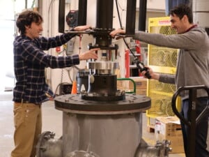 Two researchers attach a part fabricated by the APL-UW Machine Shop
