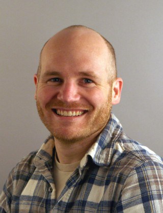 Portrait of Trevor, smiling, wearing plaid shirt
